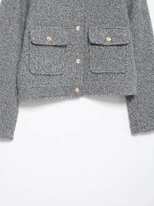 Close-up of light grey tweed jacket featuring decorative gold buttons and textured fabric