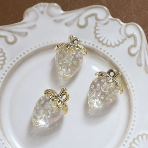 Macro view of three translucent iridescent strawberry pendants on a ceramic plate