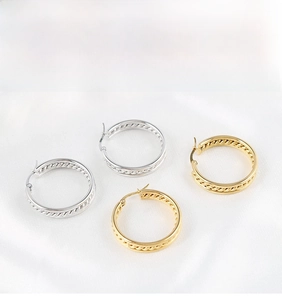 Detailed view of gold and silver textured hoop earrings on a white silk background