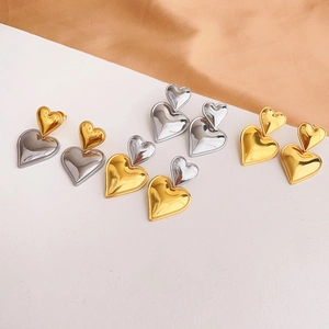 Detailed close-up of mixed gold and silver heart-shaped stainless steel earrings on satin