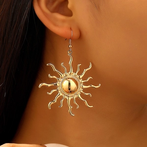 Close-up of oversized golden sunburst stud earrings on model with retro metallic finish