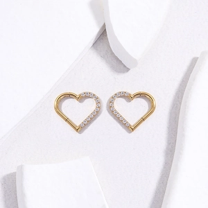 Detail view of gold titanium heart-shaped cartilage rings with zircon on gypsum stone