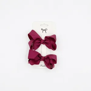 Detail of 2-piece dark red grosgrain ribbon bow hair clips on display card