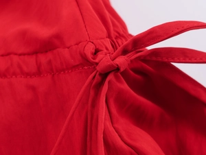 Dettaglio dell'abito midi rosso con cuciture rifinite e design con coulisse a fiocco