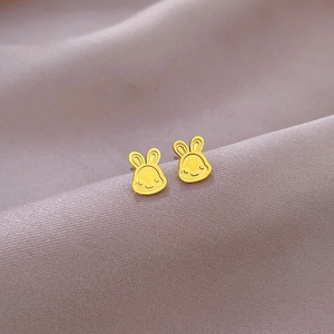 Macro detail of golden bunny stud earrings on soft purple silk fabric texture