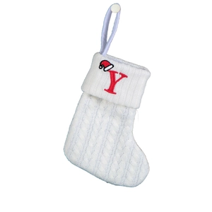 Detail of white cable knit Christmas stocking featuring a red embroidered letter Y and mini hat