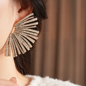 Macro view of geometric fan earrings featuring sparkling crystals and gold plating