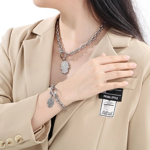 Detail der silbernen Hamsa-Hand an einer groben Gliederkette zu einem beigen Blazer