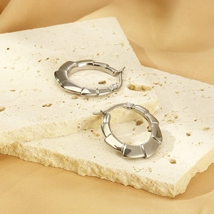 Détail macro de boucles d'oreilles en acier titane argenté au design de bambou