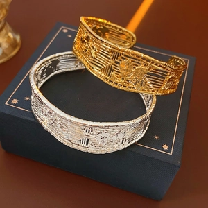 Detail of 18k gold and silver plated mesh open bangles on a blue jewelry box