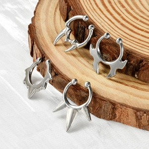 Detailed close-up of four silver U-shaped non-pierced nose rings on a wooden base