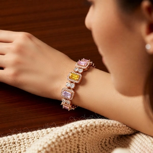 Detail of rose gold bracelet with pink and yellow zircons worn by a female model