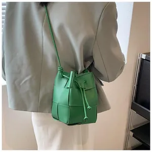 Detailed view of a green woven leather bucket bag with drawstring closure on model
