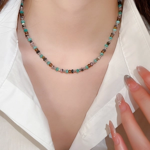 Close-up of multicolor beaded necklace with silver flower accents on female model