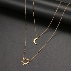 Détail du collier doré à double rangée avec pendentifs soleil et lune sur fond noir