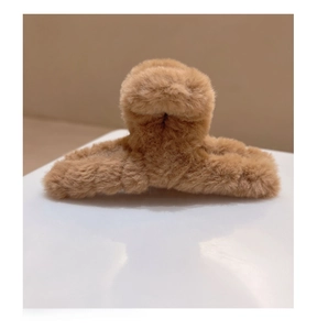 Détail de la texture en peluche marron douce et du ressort de la pince à cheveux croisée