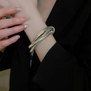 Close-up of stacked silver serpent chain bracelet with textured coiled metallic design