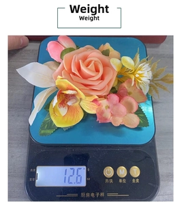 Close-up of artificial bridesmaid rose wrist flower weighing 12.6g on a digital scale