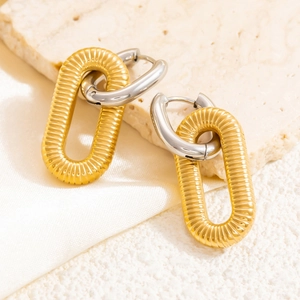 Close-up of 18k gold and silver two-tone link earrings on stone and silk texture