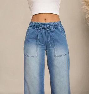 Detail van blauwe wijde jeans met elastische taille met trekkoord en denim wassing