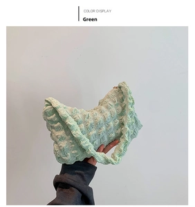 Detail of light green puff bag with quilted fabric texture and top zipper closure