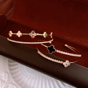 Macro shot of double-layered rose gold bangles with zircon clover details on velvet box