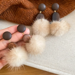 Detail of oval wood and beige pompom drop earrings featuring 925 silver needles