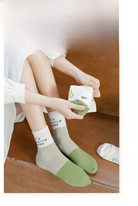 Detail showing green and white cotton crew socks with 'IT'S A GOOD WEEK' text embroidery