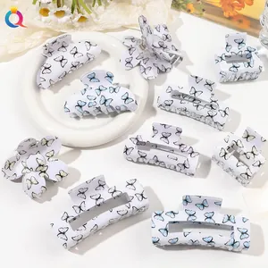 Close-up of white butterfly print hair claws in various shapes with glossy acrylic finish