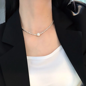 Close-up of minimalist silver irregular textured necklace with a single white pearl on a model