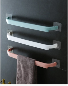 Three-color adhesive bathroom towel bars in green, white, and pink on a tile wall