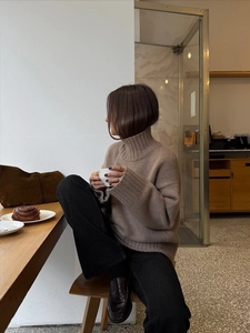 Detail shot of chunky high neck knit sweater in warm brown featuring soft texture