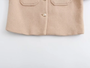 Close-up of beige wool jacket hem featuring gold metal buttons and flap pocket detail