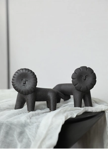 Close-up of matte black ceramic lion sculptures with fine white speckled texture and art style