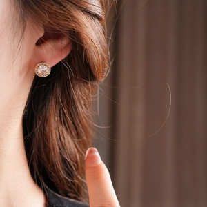Dettaglio orecchino a lobo halo dorato con zircone trasparente indossato da modella
