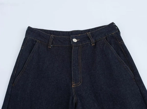 Detailed view of dark blue denim jeans waist with yellow stitching and pockets