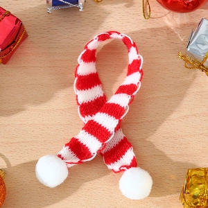 Close-up of a mini red and white striped knitted scarf with pom-poms for Christmas decor