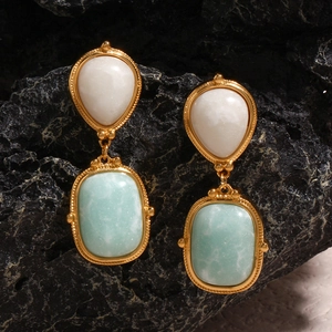 Macro detail of vintage gold earrings with amazonite stone on natural black rock