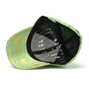 Détail de la casquette verte avec motifs de cœur dorés et imprimé LOVE sur la visière