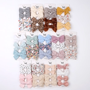 Flat lay of diverse bow hair clip set featuring plaid, floral, and velvet patterns
