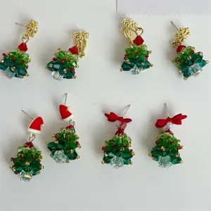 Macro shot of handmade beaded Christmas tree earrings with crystal glass and red bows