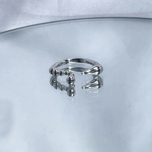 Macro shot of silver irregular open ring with teardrop shape and small metal charm