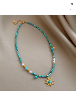 Détail du collier de perles turquoise et nacre avec pendentif soleil sur soie