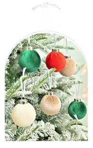 Close-up of luxury 6cm velvet Christmas balls hanging on a snowy festive tree branch