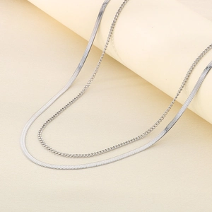 Double layered silver stainless steel snake and Cuban chain necklace set on beige stand