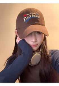 Detail of coffee brown baseball cap with white letter embroidery on a female model