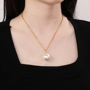 Close-up of elegant gold chain necklace with a large round white pearl on a female model