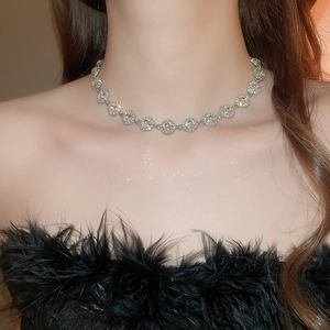 Dettaglio della collana scintillante con zirconi indossata con abito piumato elegante