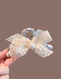 Détail d'une pince à cheveux en dentelle florale avec une grande perle centrale