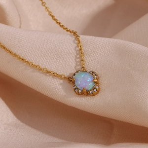 Detail of 18K gold-plated opal pendant necklace with crystal halo on silk fabric
